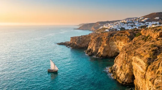 Vue panoramique sur la côte méditerranéenne du Maghreb avec falaises ocres, mer turquoise et ville blanche au crépuscule
