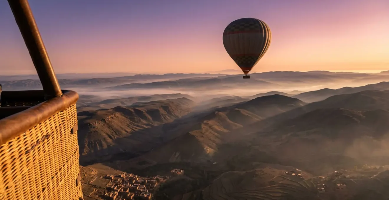 Nacelle de montgolfière survolant les contreforts de l'Atlas au lever du soleil avec ombres dorées sur le relief